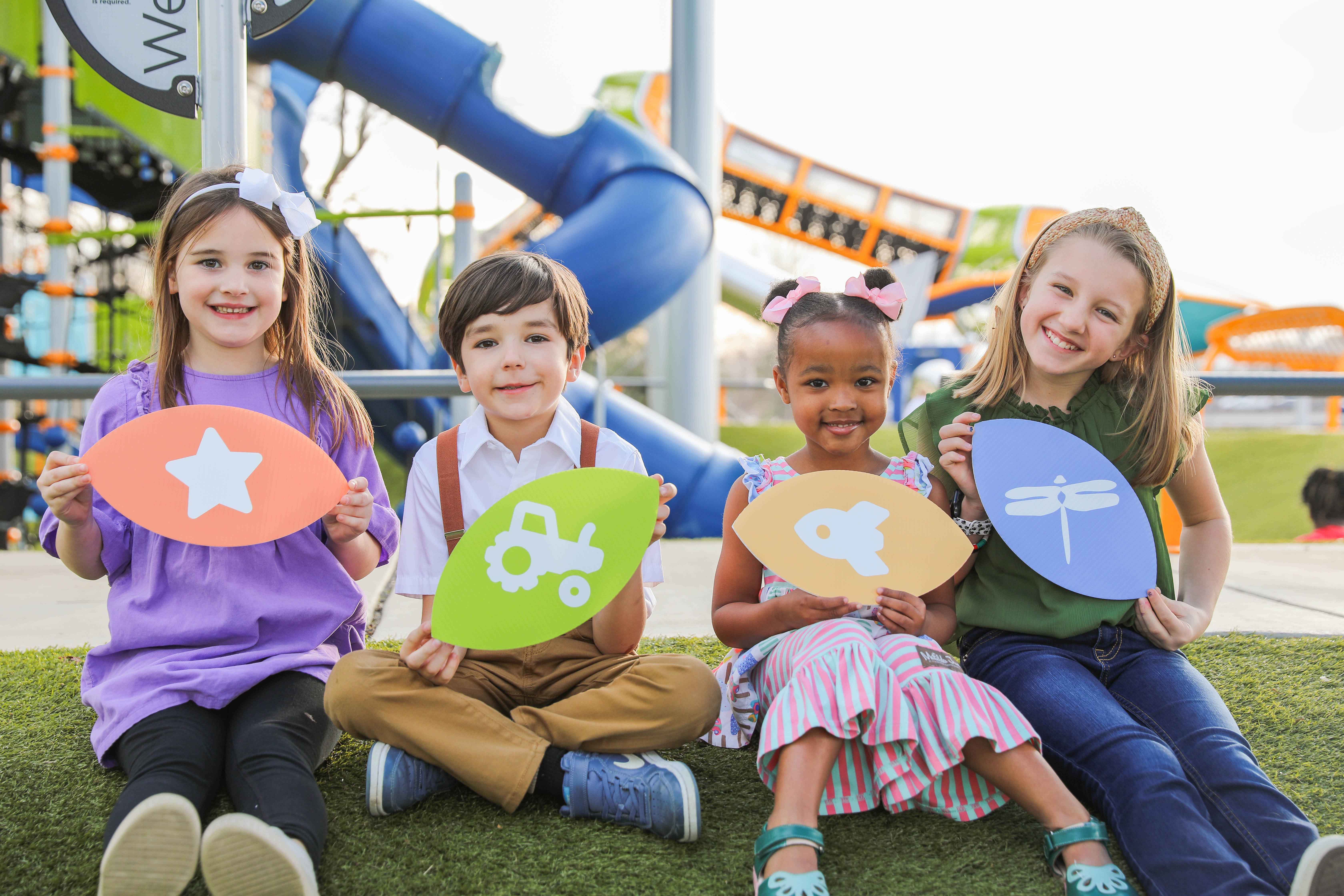 kids holding lefleur museum district logo signs on the lefleur's bluff playground